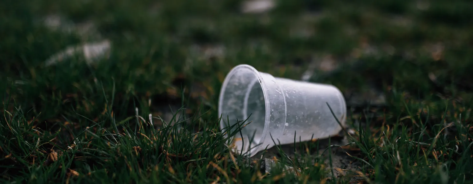 Close up of a clear plastic cup thrown in grass credit Ivan Radic